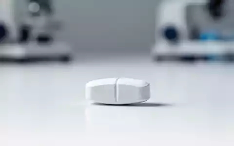 Eine einzelne pharmazeutische Tablette auf einer sauberen, weißen Laboroberfläche als Symbol für moderne Adipositas-Therapie. - Foto: über boerse-global.de