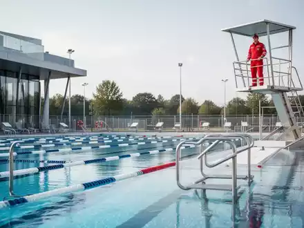 Ein Rettungsschwimmer beobachtet ein Freibad von einem Hochsitz aus, um die Sicherheit der Badegäste zu gewährleisten. - Foto: über boerse-global.de