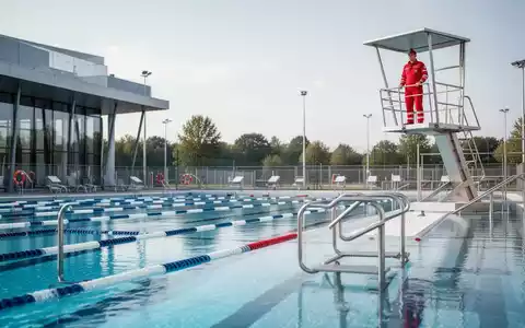 Ein Rettungsschwimmer beobachtet ein Freibad von einem Hochsitz aus, um die Sicherheit der Badegäste zu gewährleisten. - Foto: über boerse-global.de