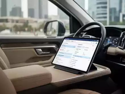 Innenraum eines Firmenfahrzeugs mit einem Tablet auf dem Sitz, das logistische Arbeitsdaten anzeigt. - Foto: über boerse-global.de
