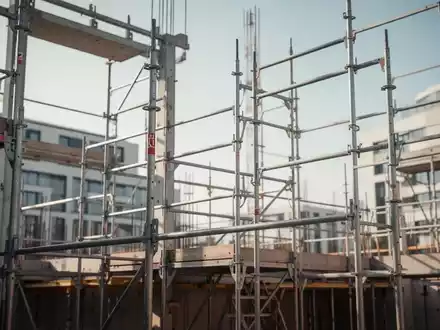 Moderne Baustelle im deutschen Bauhauptgewerbe mit Stahlgerüsten und architektonischen Strukturen bei klarem Tageslicht. - Foto: über boerse-global.de