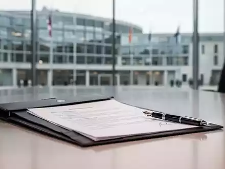 Ein minimalistischer Schreibtisch mit Dokumenten und einem Füller in einem modernen Büro als Symbol für Arbeitsrechtsreformen. - Foto: über boerse-global.de