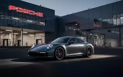 Ein moderner Porsche vor einem Produktionsgebäude bei Dämmerung, symbolisierend die aktuelle Restrukturierung. - Foto: über boerse-global.de
