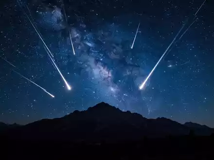 Sternschnuppenregen der Perseiden über einer nächtlichen Berglandschaft unter einem klaren Sternenhimmel. - Foto: über boerse-global.de