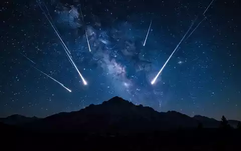 Sternschnuppenregen der Perseiden über einer nächtlichen Berglandschaft unter einem klaren Sternenhimmel. - Foto: über boerse-global.de