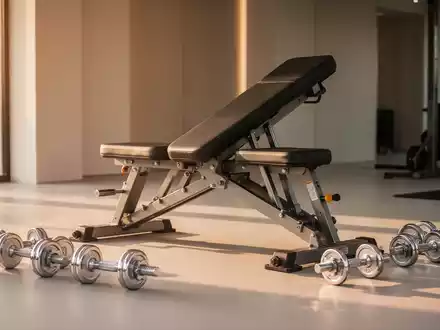 Modernes Heimfitness-Studio mit Hanteln und Trainingsgeräten bei warmem Sonnenlicht. - Foto: über boerse-global.de
