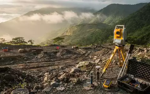Geologisches Erkundungsgebiet in einer grünen Berglandschaft mit Vermessungsausrüstung. - Foto: über boerse-global.de