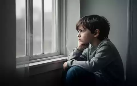 Ein nachdenkliches Kind sitzt allein an einem Fenster, symbolisch für die psychische Belastung junger Menschen. - Foto: über boerse-global.de