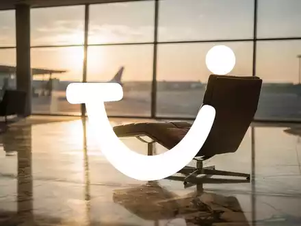 Abstrakte Darstellung einer luxuriösen Flughafen-Lounge bei Sonnenuntergang als Symbol für die Reisebranche. - Foto: über boerse-global.de