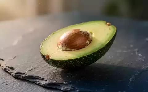Eine halbierte reife Avocado auf einer dunklen Steinoberfläche als Symbol für gesunde Ernährung. - Foto: über boerse-global.de