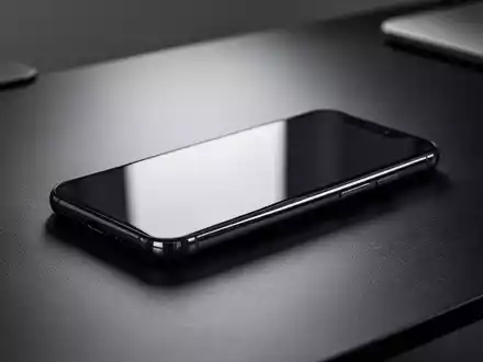 Ein modernes Smartphone auf einem dunklen Schreibtisch in professioneller, stimmungsvoller Beleuchtung. - Foto: über boerse-global.de