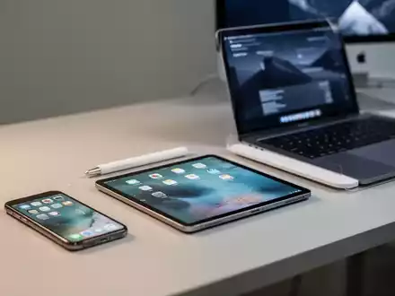 Sauberer, moderner Arbeitsplatz mit iPhone, iPad und MacBook auf einem Schreibtisch, die Apple-Geräteversicherung darstellen. - Foto: über boerse-global.de
