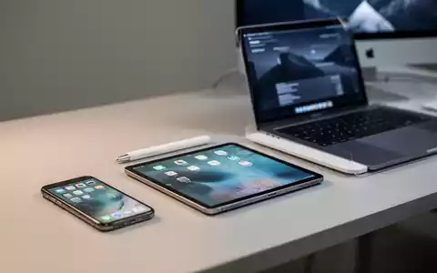 Sauberer, moderner Arbeitsplatz mit iPhone, iPad und MacBook auf einem Schreibtisch, die Apple-Geräteversicherung darstellen. - Foto: über boerse-global.de