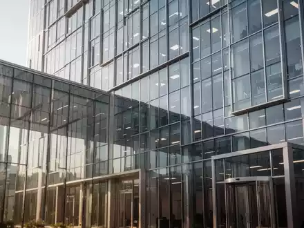 Moderne Glasfassade eines Bürogebäudes bei Tageslicht, Symbolbild für juristische Auseinandersetzungen in der Industrie. - Foto: über boerse-global.de