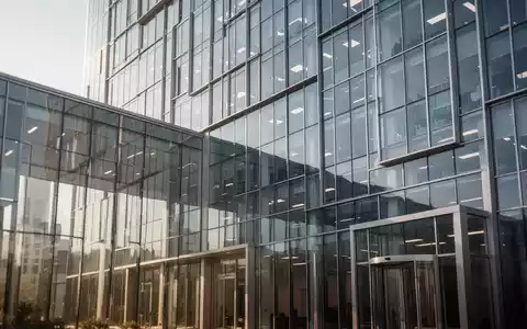 Moderne Glasfassade eines Bürogebäudes bei Tageslicht, Symbolbild für juristische Auseinandersetzungen in der Industrie. - Foto: über boerse-global.de