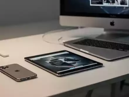 Sauberer Arbeitsplatz mit iPhone, iPad und MacBook, Symbol für die Bündelung mehrerer Geräteversicherungen. - Foto: über boerse-global.de