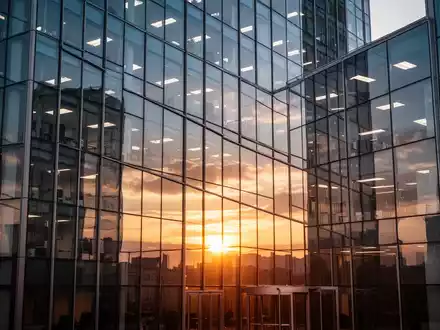 Moderne Bürogebäude-Fassade bei Sonnenaufgang als Symbol für wirtschaftliche Wende und finanzielle Stabilität. - Foto: über boerse-global.de