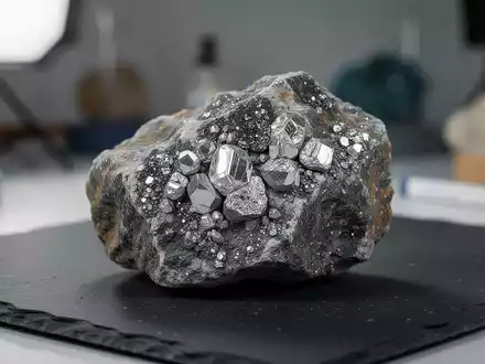 Nahaufnahme einer lithiumhaltigen Gesteinsprobe mit sichtbaren Mineralkristallen in einem geologischen Labor. - Foto: über boerse-global.de