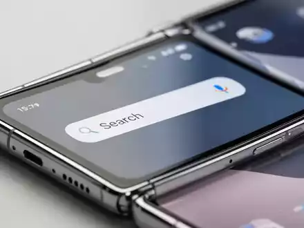 Nahaufnahme eines modernen faltbaren Smartphones mit der neuen One UI 9 Benutzeroberfläche und integrierter Suchleiste. - Foto: über boerse-global.de