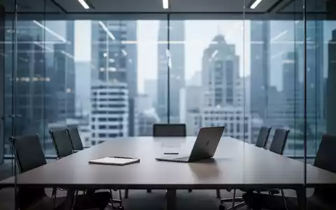 Modernes, minimalistisches Büro mit Konferenztisch und Laptop vor einer Glasfassade. - Foto: über boerse-global.de