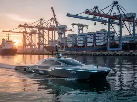 Autonomes unbemanntes Wasserfahrzeug nahe einer modernen Werft mit Portalkränen. - Foto: über boerse-global.de