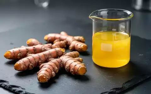 Frische Kurkuma-Wurzeln neben einem Glasgefäß mit gelbem Curcumin-Extrakt in einer Laborumgebung. - Foto: über boerse-global.de