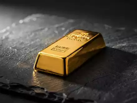 Ein glänzender Goldbarren auf einer dunklen Schieferplatte mit dramatischem Licht. - Foto: über boerse-global.de