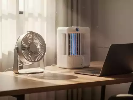 Moderner Home-Office-Arbeitsplatz mit kompakten Kühlgeräten und Ventilator auf dem Schreibtisch bei sonnigem Licht. - Foto: über boerse-global.de