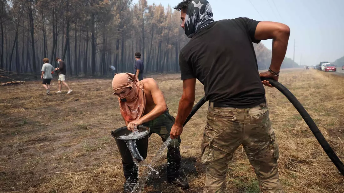 Die Einsatzkräfte und auch freiwillige bekämpfen die Flammen. - Bild: Romain Perrocheau/AFP/dpa