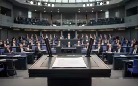 Das Rednerpult im Deutschen Bundestag vor dem unscharfen Plenarsaal bei einer politischen Sitzung. - Foto: über boerse-global.de