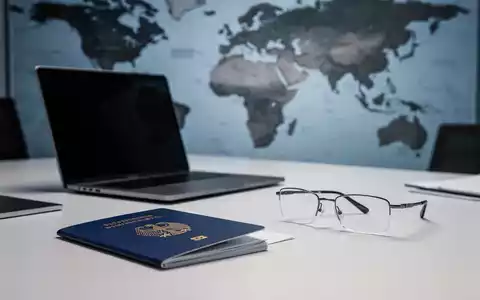 Ein Laptop und ein Reisepass auf einem Schreibtisch als Symbol für die Geschäftsführung einer GmbH aus dem Ausland. - Foto: über boerse-global.de