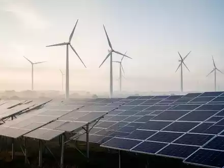 Moderne Windkraftanlage und Solarpaneele in einer weitläufigen Landschaft bei neutralem Tageslicht. - Foto: über boerse-global.de