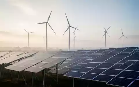 Moderne Windkraftanlage und Solarpaneele in einer weitläufigen Landschaft bei neutralem Tageslicht. - Foto: über boerse-global.de