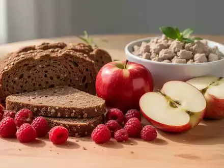 Verschiedene gesunde Lebensmittel wie Vollkornbrot, Himbeeren und Äpfel auf einem Holztisch zur Nährstoffanalyse. - Foto: über boerse-global.de
