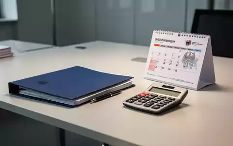 Ein Schreibtisch in einem modernen Büro mit Aktenordner, Taschenrechner und Kalender als Symbol für die Grundsicherung. - Foto: über boerse-global.de