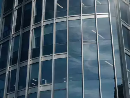 Moderne Glasfassade eines Bürogebäudes mit Spiegelungen, symbolisch für Finanzmärkte und Indexfonds. - Foto: über boerse-global.de