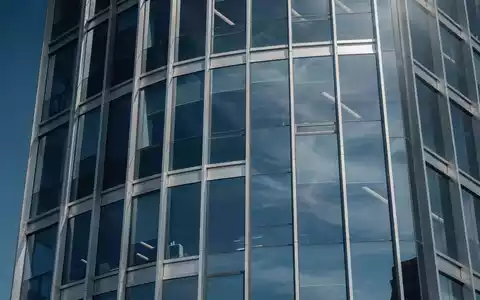 Moderne Glasfassade eines Bürogebäudes mit Spiegelungen, symbolisch für Finanzmärkte und Indexfonds. - Foto: über boerse-global.de