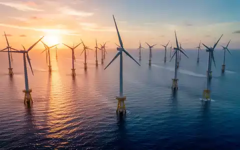 Mehrere große Offshore-Windkraftanlagen im Meer während des Sonnenuntergangs. - Foto: über boerse-global.de