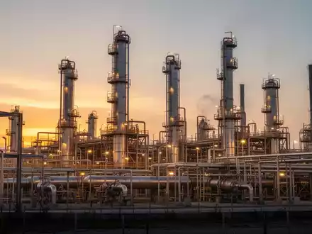 Moderne Ölraffinerie bei Sonnenuntergang mit industriellen Anlagen und atmosphärischer Beleuchtung. - Foto: über boerse-global.de