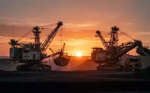 Moderne Bergbauanlage bei Sonnenaufgang mit Industriemaschinen vor einem leuchtenden Horizont. - Foto: über boerse-global.de