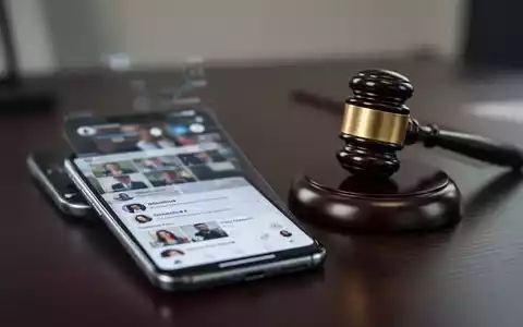 Ein Smartphone mit Social-Media-Profil neben einem Richterhammer auf einem Schreibtisch als Symbol für rechtliche Folgen. - Foto: über boerse-global.de