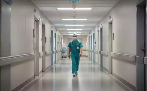 Ein medizinischer Mitarbeiter in einem modernen Krankenhausflur steht symbolisch für die Herausforderungen der Pflege. - Foto: über boerse-global.de