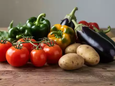 Frisches Gemüse wie Tomaten, Paprika, Auberginen und Kartoffeln auf einem Holztisch bei natürlichem Licht. - Foto: über boerse-global.de