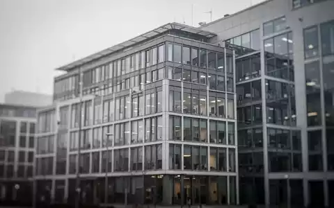 Ein modernes Bürogebäude an einem bewölkten Tag als Symbol für die aktuelle konjunkturelle Schwäche am Arbeitsmarkt. - Foto: über boerse-global.de