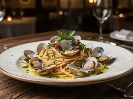 Ein Teller mit Linguine alle Vongole auf einem rustikalen Holztisch in einem italienischen Restaurant. - Foto: über boerse-global.de