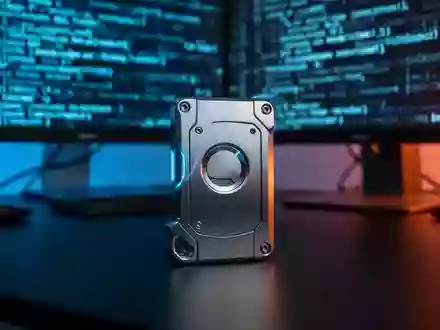 Krypto-Hardware-Wallet auf dunklem Schreibtisch mit verschwommenem digitalem Code im Hintergrund, Symbol für Cybersicherheit. - Foto: über boerse-global.de