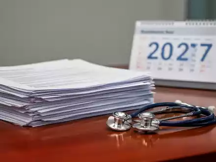 Stapel mit Gesetzestexten und einem Stethoskop auf einem Schreibtisch vor einem verschwommenen Kalender. - Foto: über boerse-global.de
