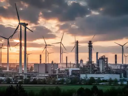 Moderne deutsche Industrieanlage mit Windkraftanlagen vor einem dramatischen Himmel bei Sonnenaufgang. - Foto: über boerse-global.de