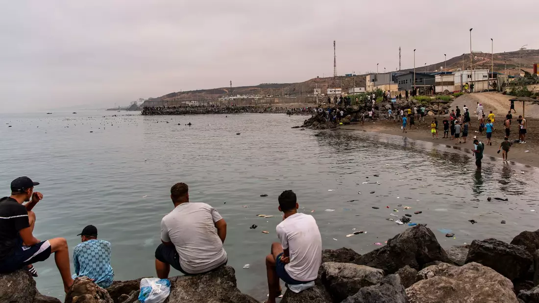 Migranten blickten von Felsen aus, während andere aus der spanischen Enklave Ceuta nach Marokko zurückkehrten. - Bild: Antonio Sempere/AP/dpa