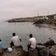 Migranten blickten von Felsen aus, während andere aus der spanischen Enklave Ceuta nach Marokko zurückkehrten. - Bild: Antonio Sempere/AP/dpa